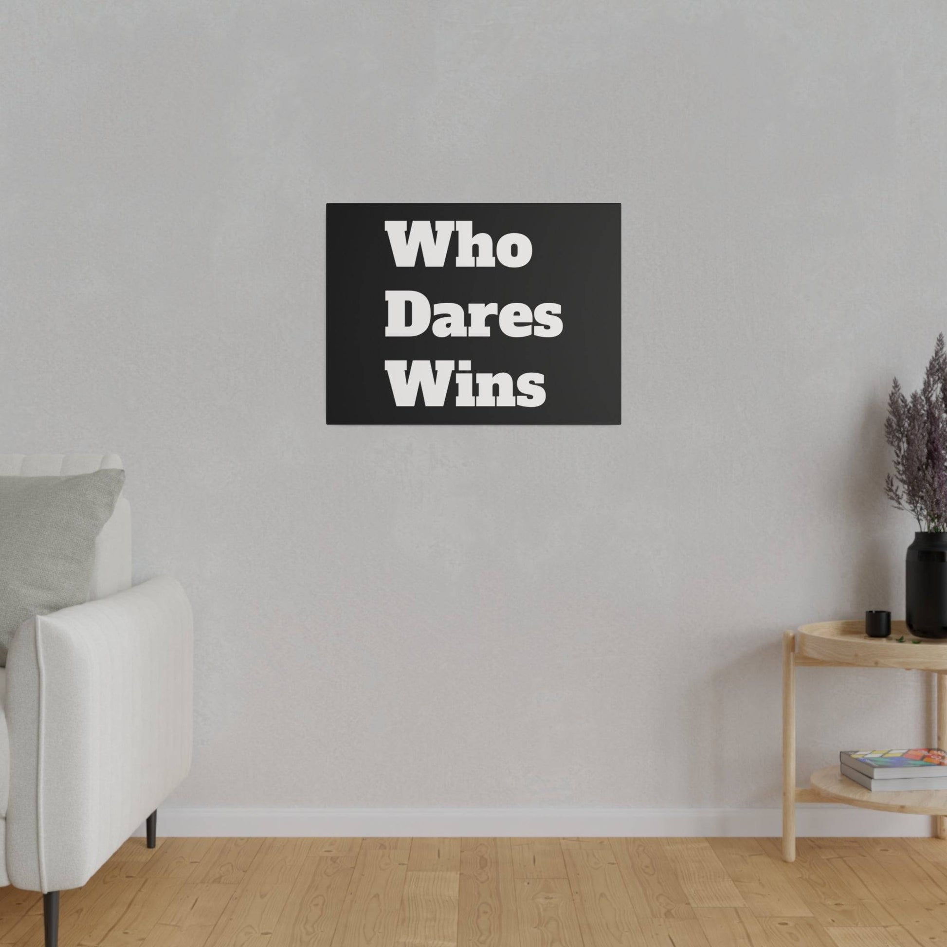 Black wall art with white "Who Dares Wins" lettering hangs on a light gray wall above a wooden floor.