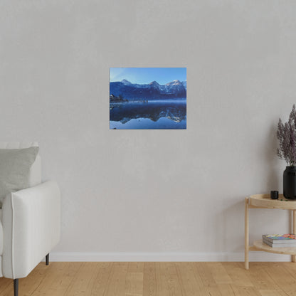 Small square wall art showing a blue winter lake with snow-capped mountains reflected in calm water.