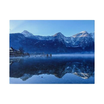 Blue alpine lake reflects snow-capped mountains and a wooden pier with small houses along the shore.